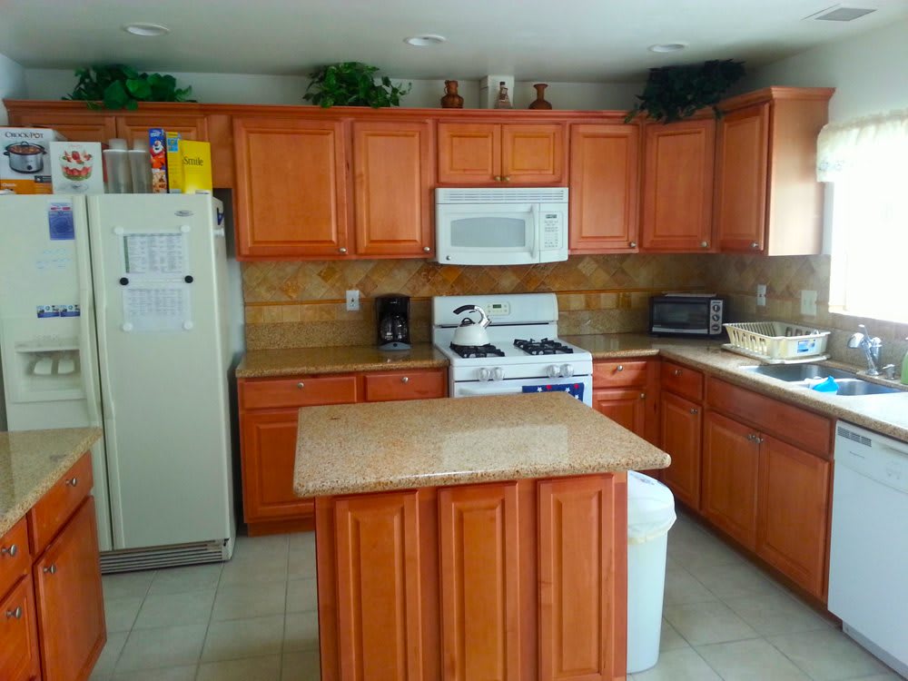 A modern kitchen with wooden cabinets, a central island, and various appliances.