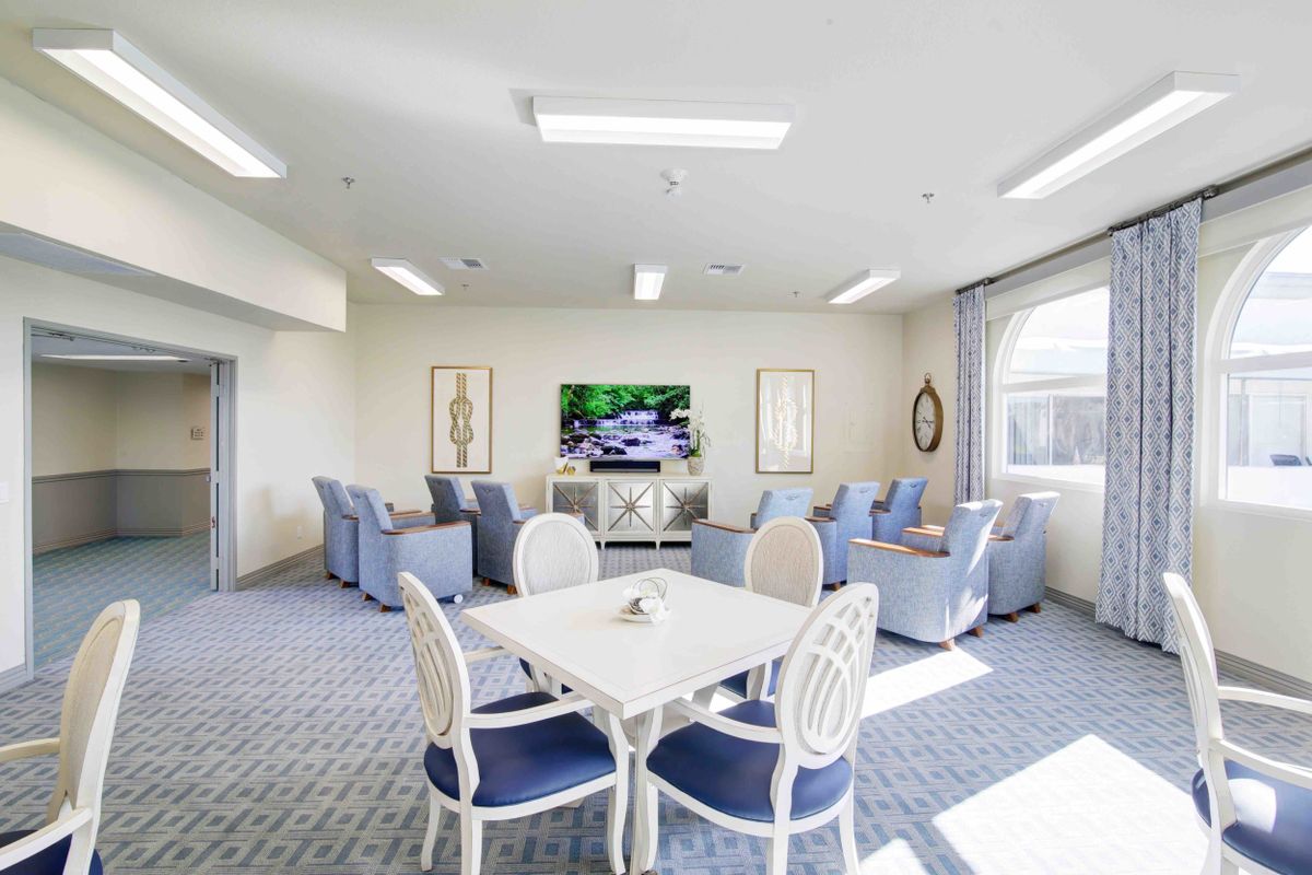A bright living room with a seating area, television, and dining table.