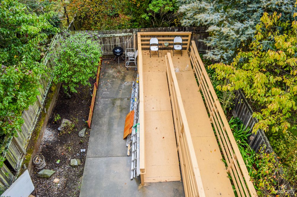 An outdoor bocce court surrounded by lush greenery and a wooden fence.