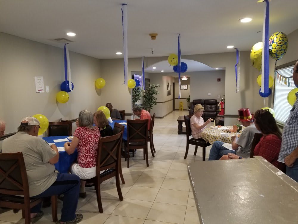 A group of seniors gathered in a decorated room with yellow and blue balloons.