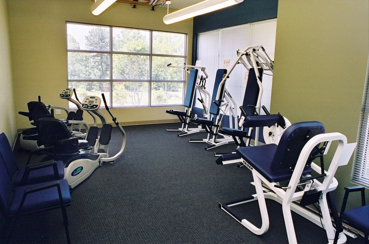 A well-lit gym featuring various exercise machines and fitness equipment.