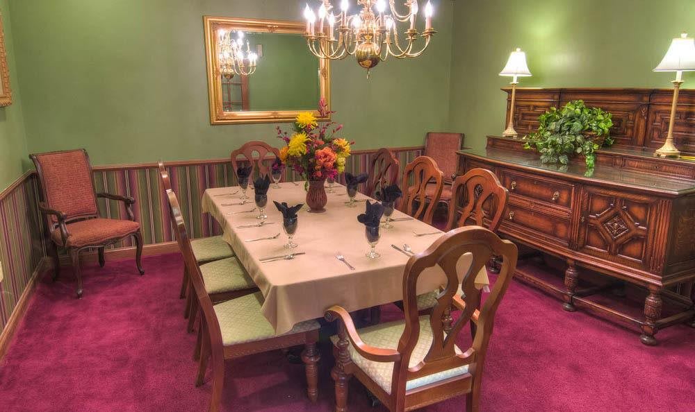 A formal dining room with a set table, chandelier, and elegant decor.