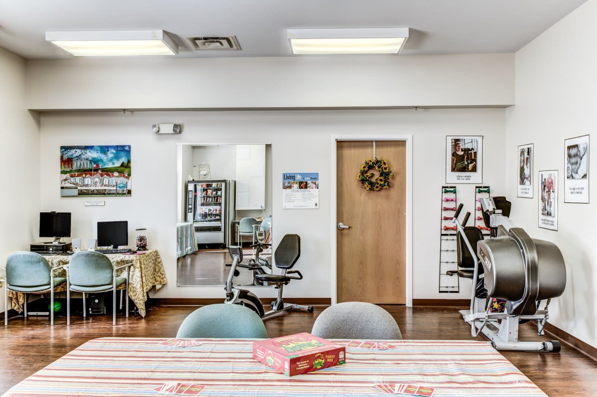 A room with computers, exercise equipment, and a table with a board game.