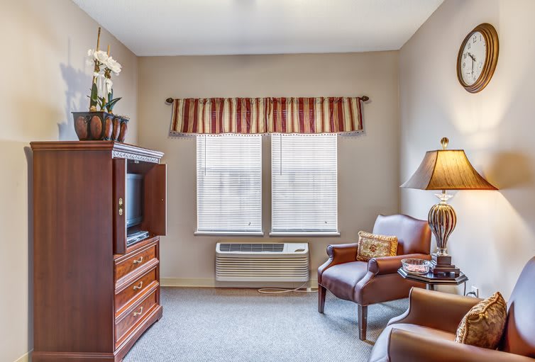 A cozy living room with a TV, sofa, and a window letting in natural light.