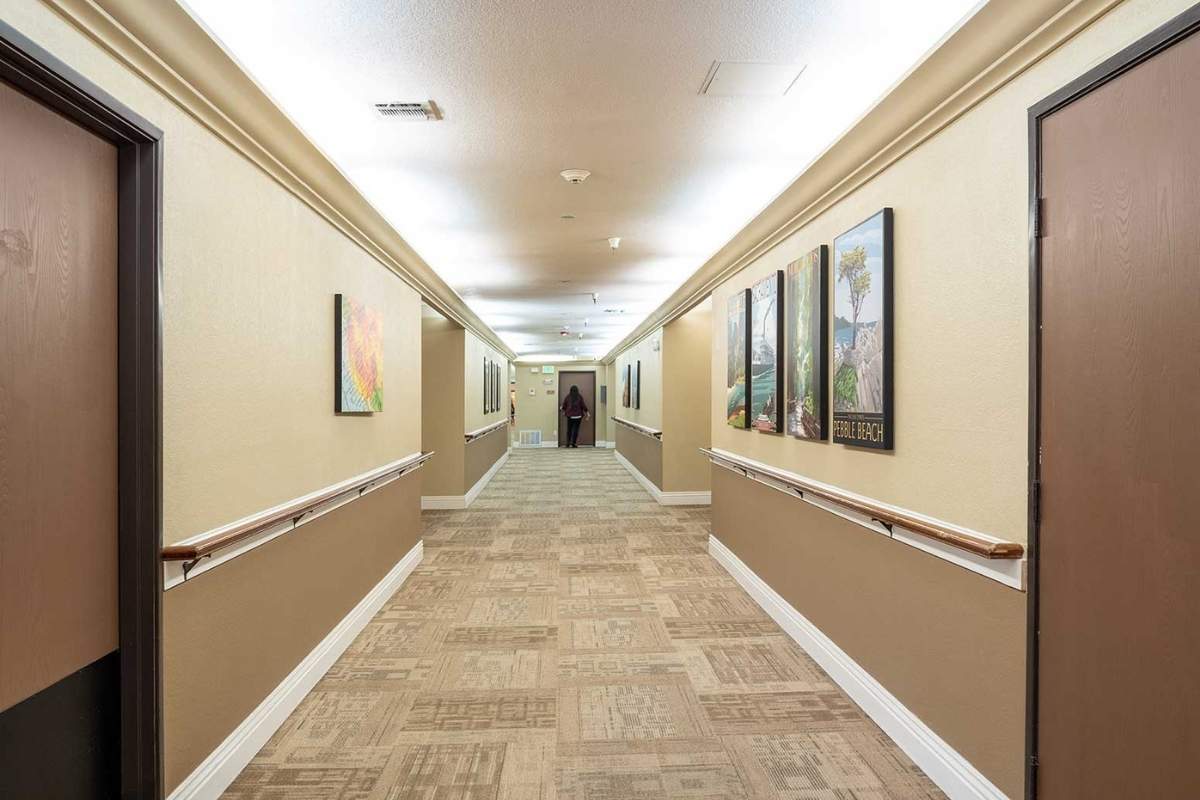 A well-lit hallway with artwork on the walls and tiled flooring.
