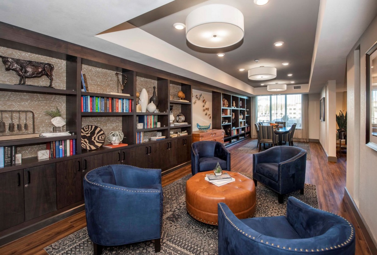 Comfortable lounge area with blue chairs and bookshelves.