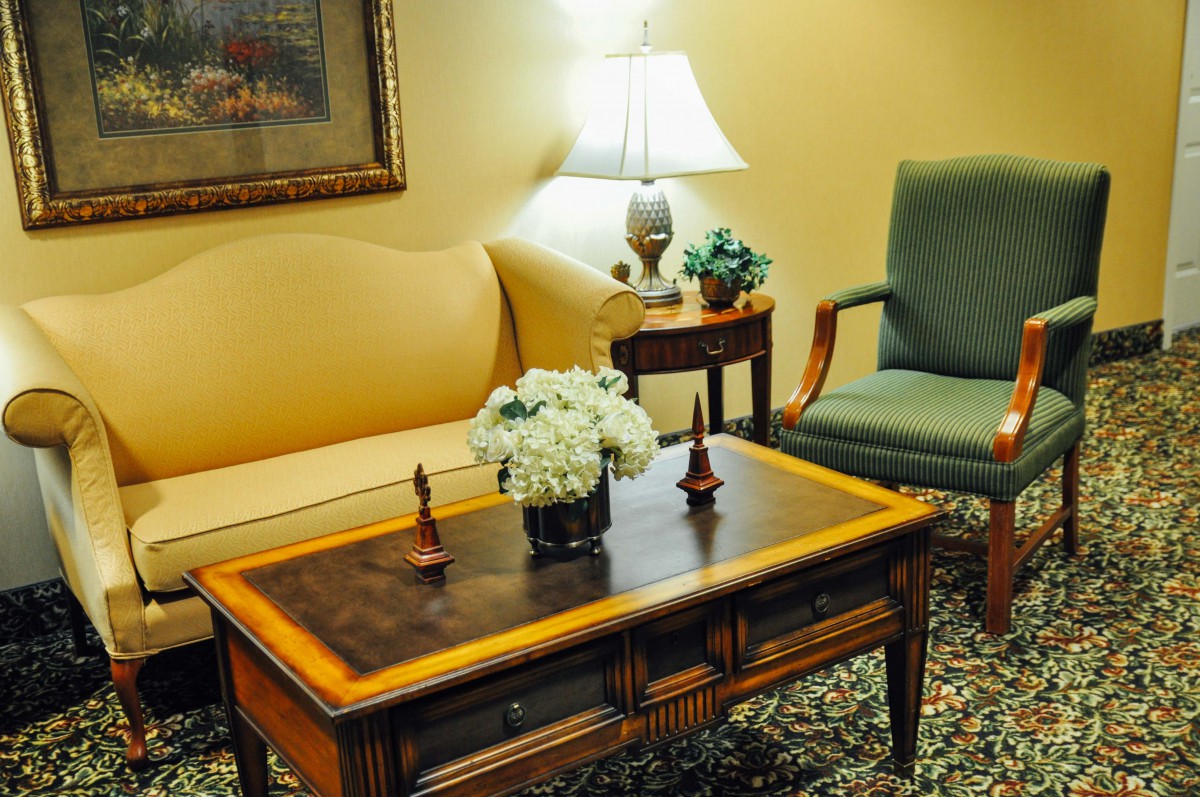 A cozy living room setup with a sofa, armchair, coffee table, and decorative flowers.