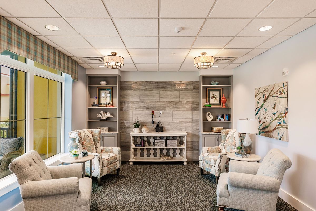 A cozy living room with neutral tones, featuring comfortable armchairs, decorative shelves, and soft lighting.