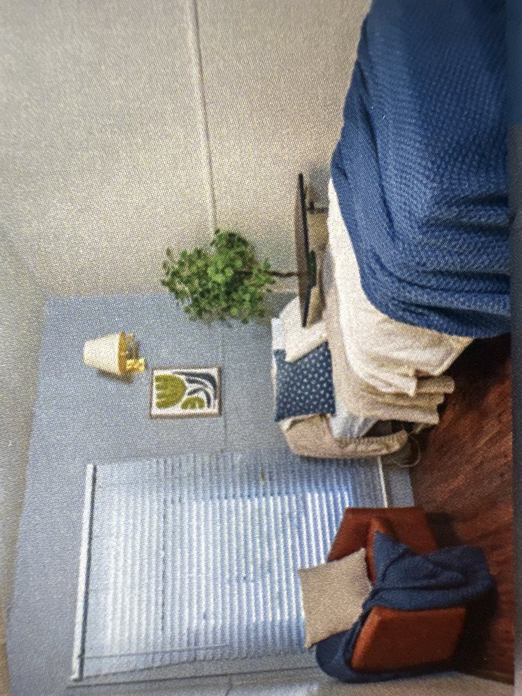 A cozy bedroom with blue-themed decor and natural light from a window.