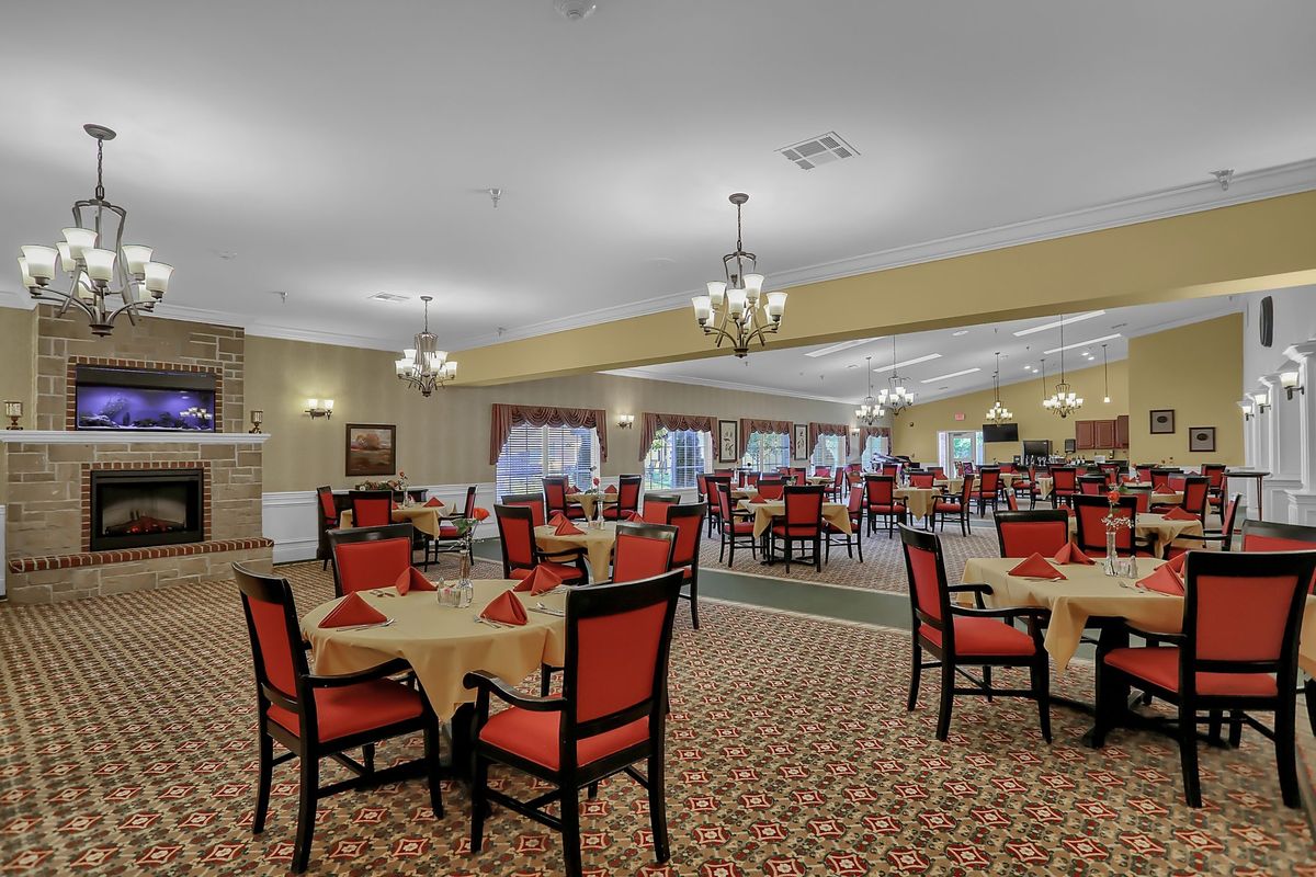 A spacious dining area with red-accented chairs and elegant chandeliers.