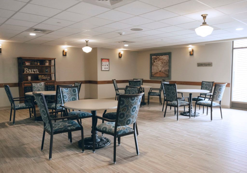 An empty dining area with tables and chairs arranged neatly under ceiling lights.