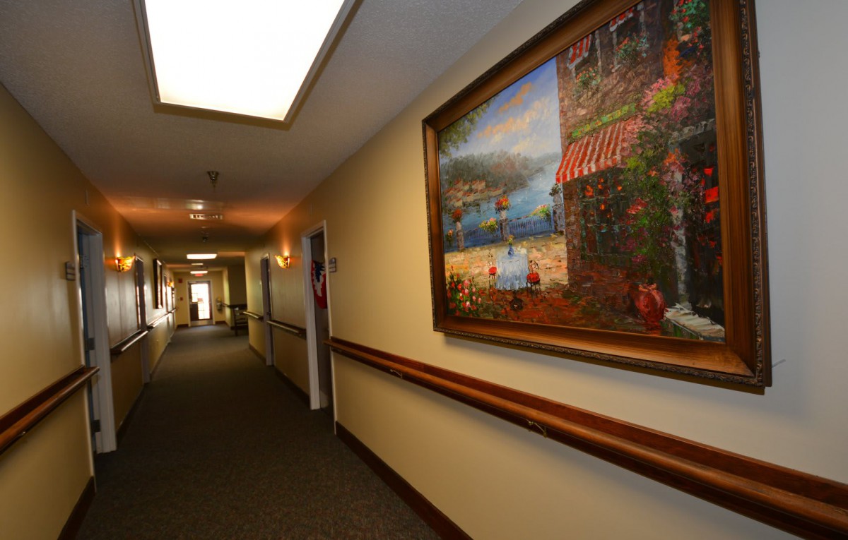 A well-lit hallway with a colorful painting on the wall.