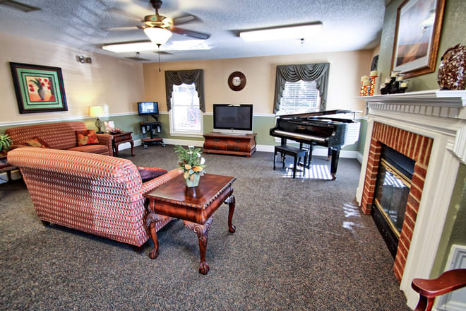A cozy living room featuring a piano, television, and fireplace with comfortable seating.