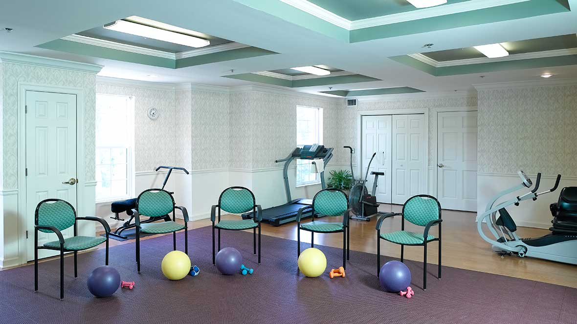 A small gym room with exercise equipment and seating.