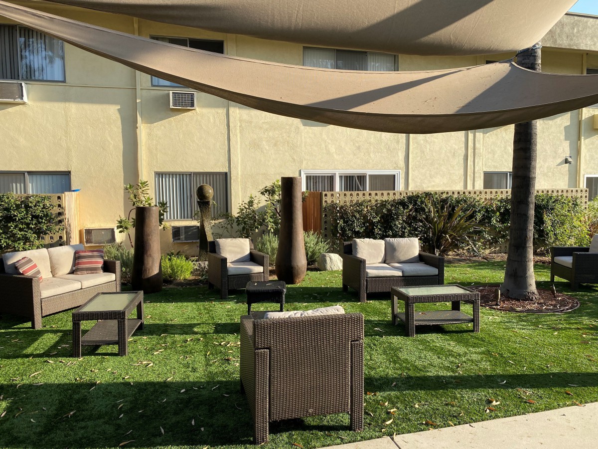 A cozy outdoor seating area with patio furniture and a shade sail on a sunny day.