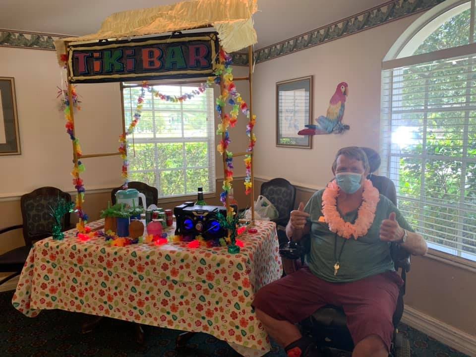 A festive tiki-themed indoor party setup with decorations and a person wearing a mask and leis.
