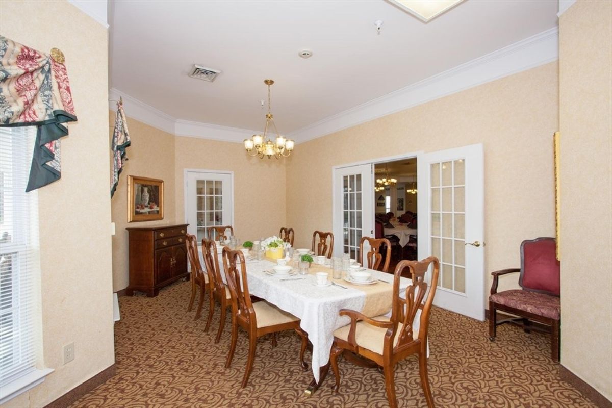 A well-appointed dining room with a large table and elegant chairs, illuminated by a chandelier.