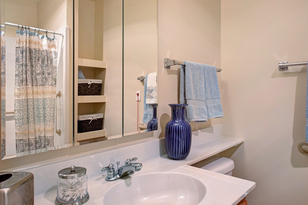 A well-organized bathroom with a sink, mirror, and blue accents.