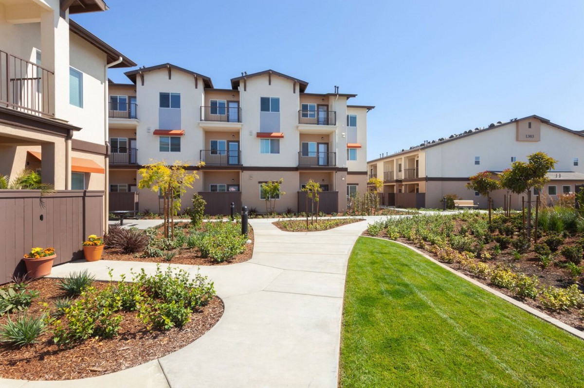 A modern apartment complex with well-maintained landscaping and pathways.