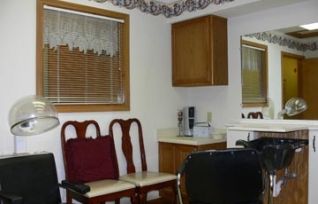 A small room with wooden chairs, a mirror, and a window with blinds.