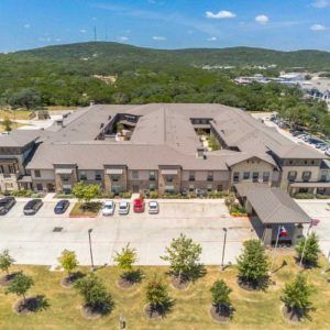Aerial view of a large building with a parking lot and surrounding landscape.