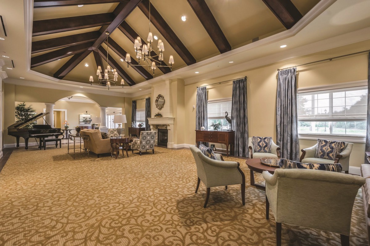 A spacious and elegantly designed living room featuring chandeliers, a vaulted ceiling, and comfortable seating areas.