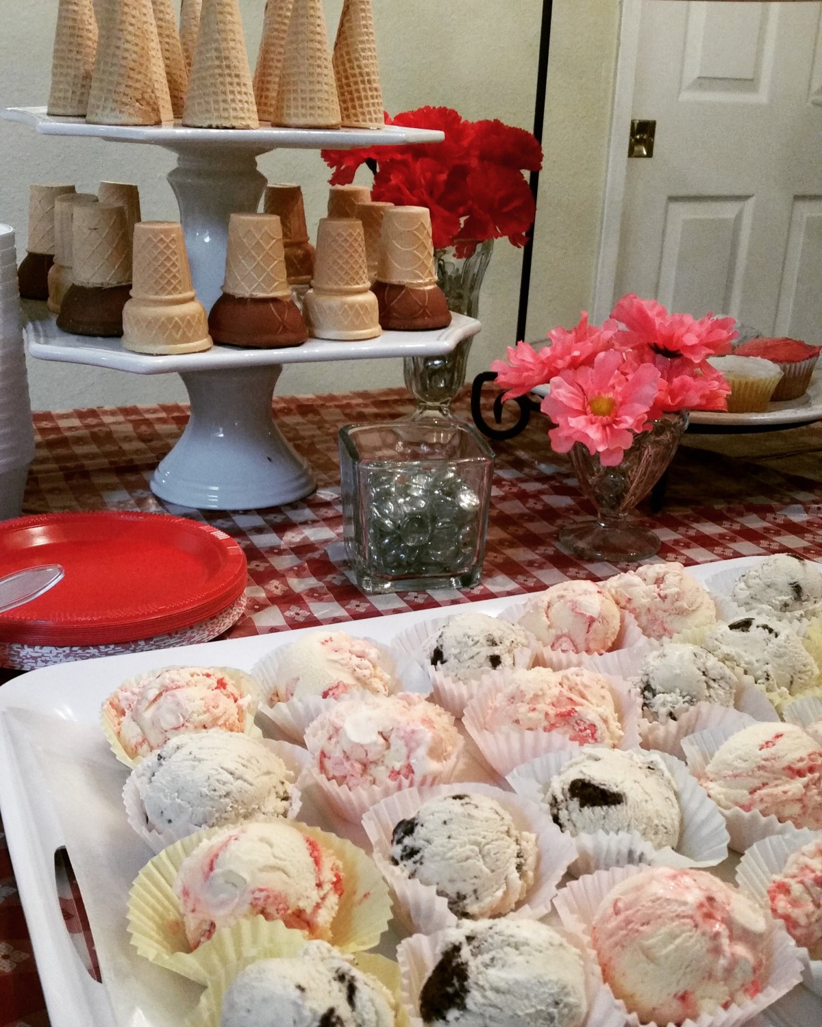 A festive dessert table featuring assorted ice creams and cone treats.