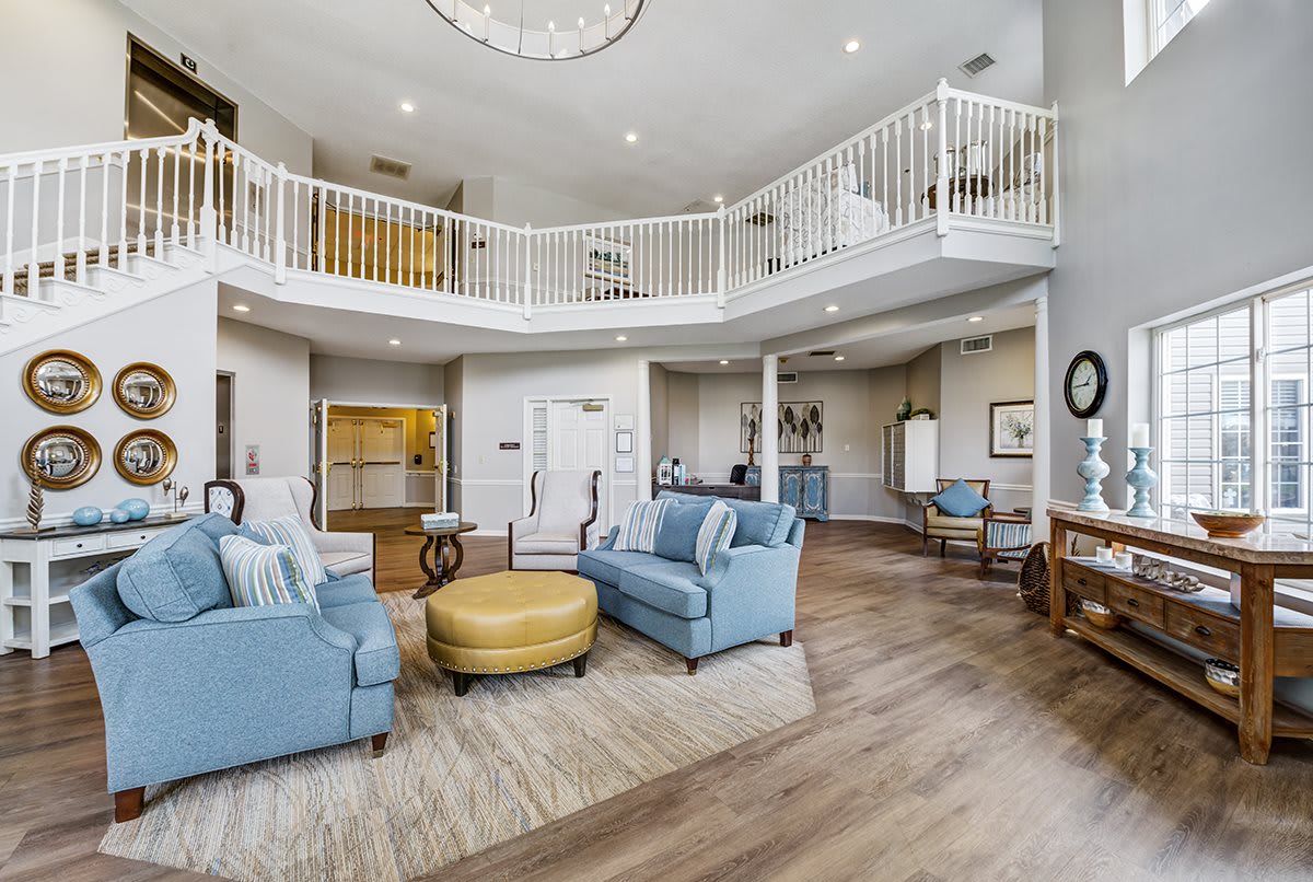 A spacious and modern living room with blue sofas, an open floor plan, and a mezzanine balcony.
