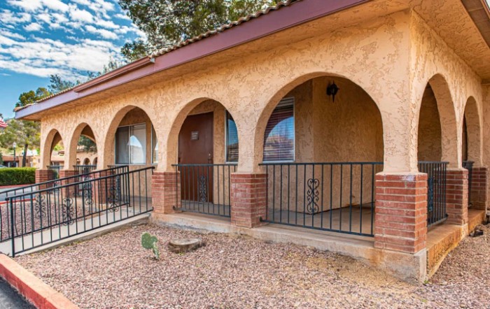A house exterior featuring arched doorways and a brick porch railing.
