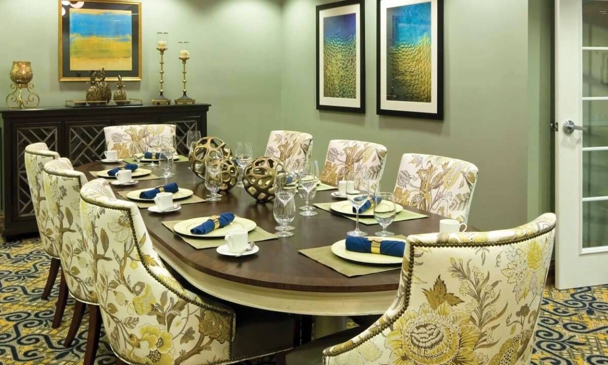 A beautifully arranged dining room featuring an elegant table setting with floral chairs and framed artwork on the walls.