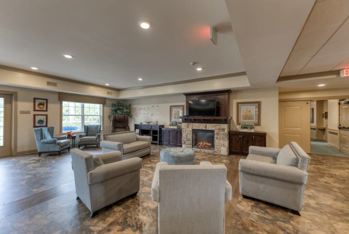 A modern and comfortable living room with ample seating, featuring a fireplace and television.