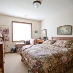 Cozy bedroom interior with a floral patterned bedspread and natural lighting.