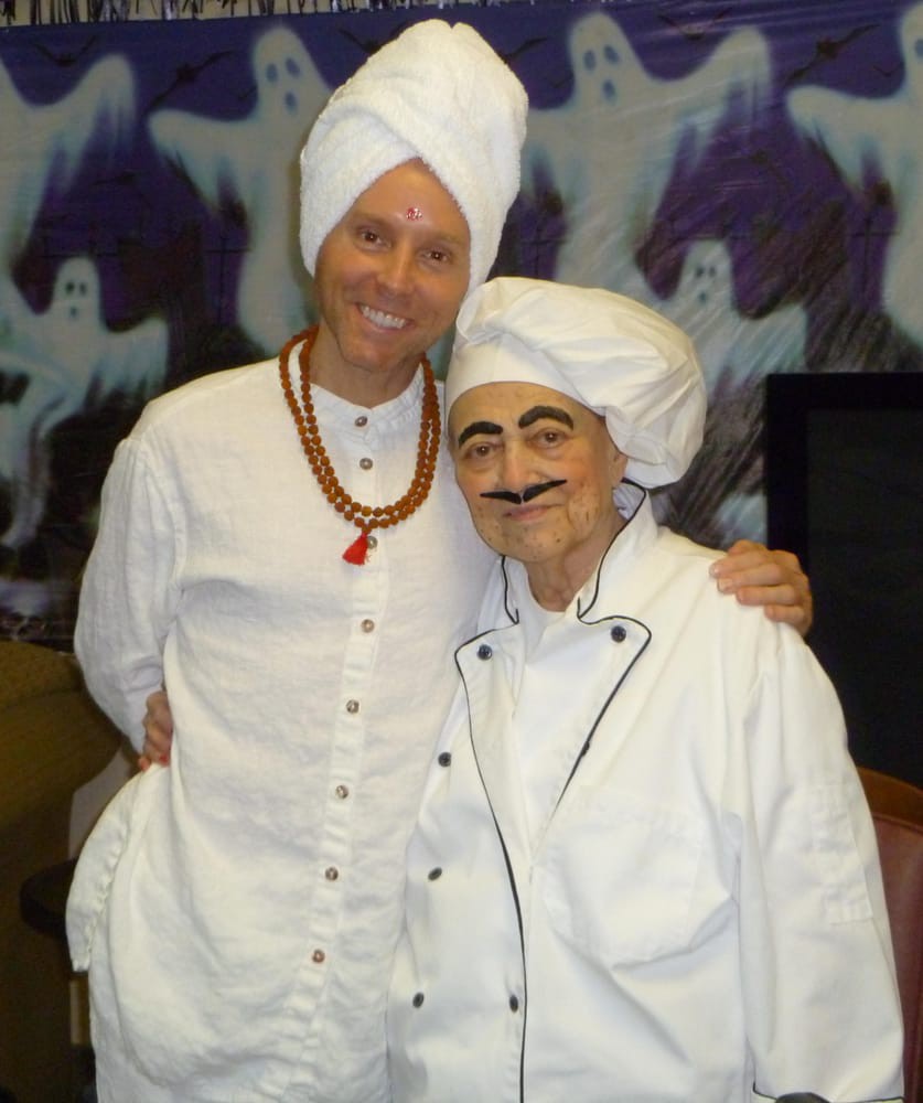 Two people dressed in costumes, wearing white chef hats and smiling for a photo.
