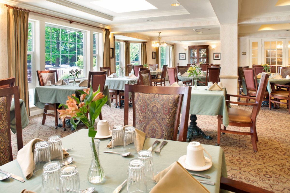 Elegant dining area with neatly arranged tables and chairs, surrounded by large windows.