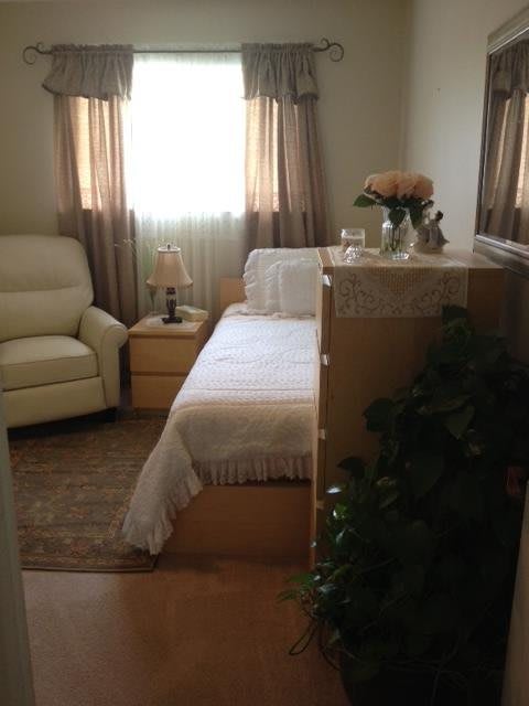 A cozy bedroom with a single bed, armchair, and decorative elements.