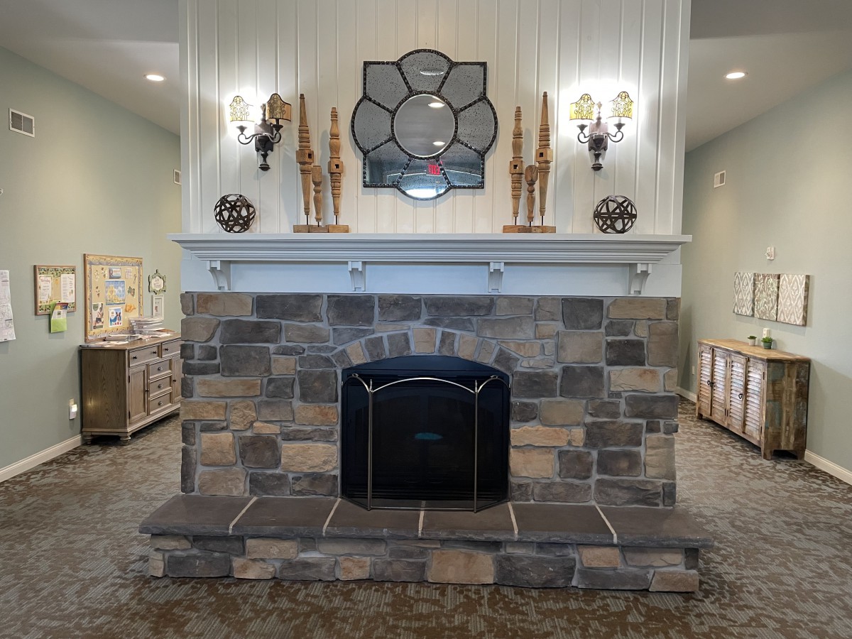 A beautifully designed stone fireplace with elegant decor, featuring a large mirror and wall sconces.