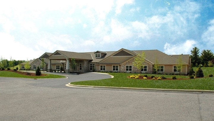 A suburban residential building with a neatly landscaped front yard under a partly cloudy sky.