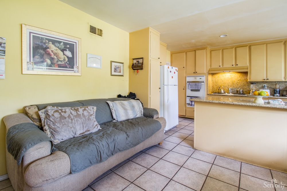 A cozy living room with a sofa and an open-concept kitchen featuring modern appliances.