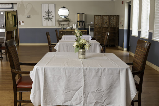 An elegantly set dining area featuring tables with white tablecloths and a floral centerpiece, creating a serene atmosphere.