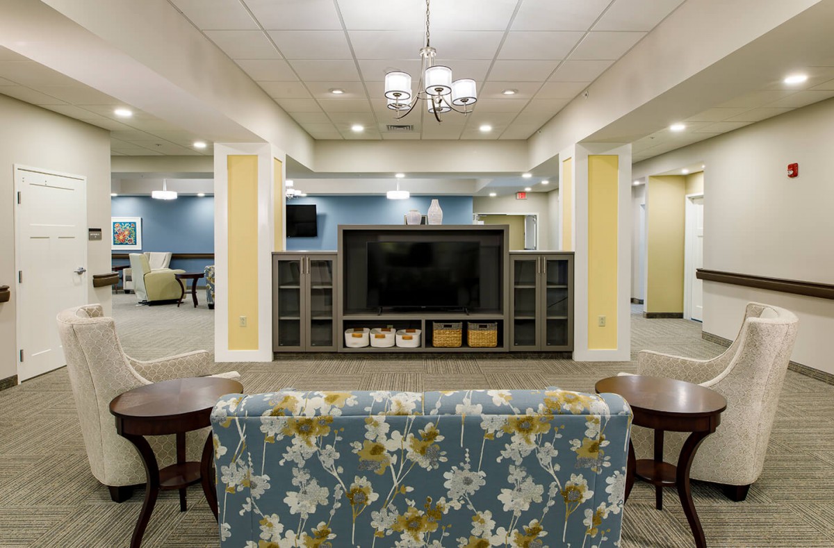A spacious and elegantly designed living room with a large television, comfortable seating, and stylish decor.