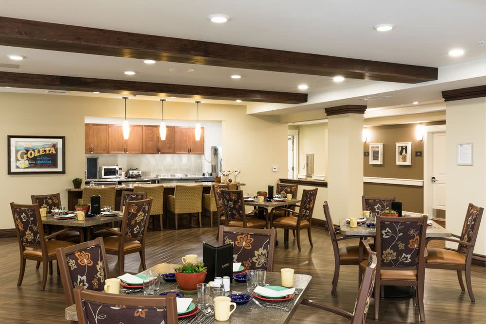 A cozy dining area with neatly arranged tables and chairs, featuring warm lighting and elegant decor.