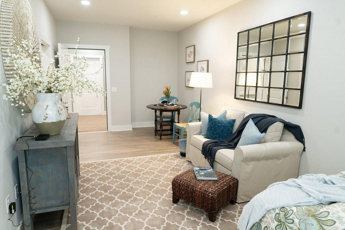 A cozy and neatly arranged living room with neutral tones, featuring comfortable seating, a stylish rug, and decorative elements.