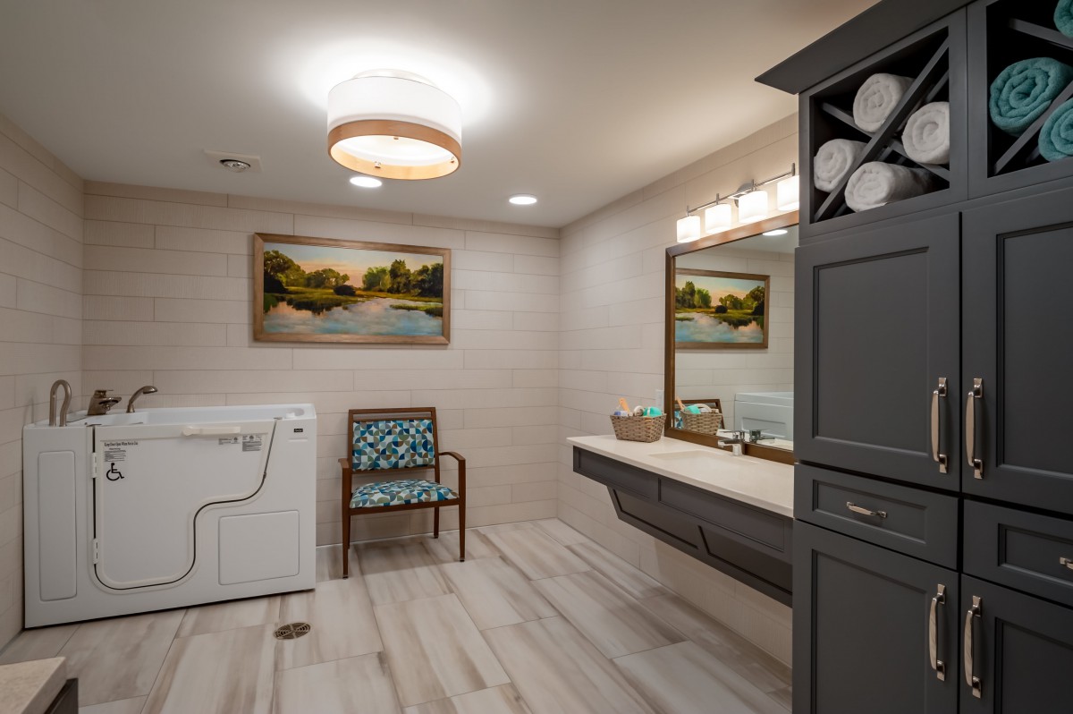 A modern bathroom featuring a vanity mirror, laundry machine, and artwork on the wall.