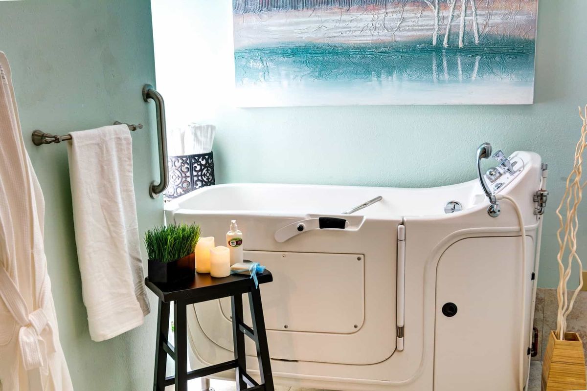 A modern bathroom featuring a walk-in tub with decorative elements like candles and a towel rack.