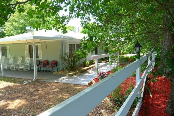 A cozy cottage with a garden path lined by trees and flowers.