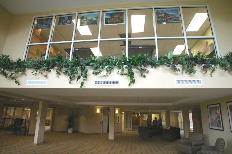 A spacious lobby area featuring large windows and greenery with seating arrangements.