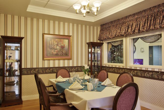 An elegant dining room with a well-set table and striped wallpaper.