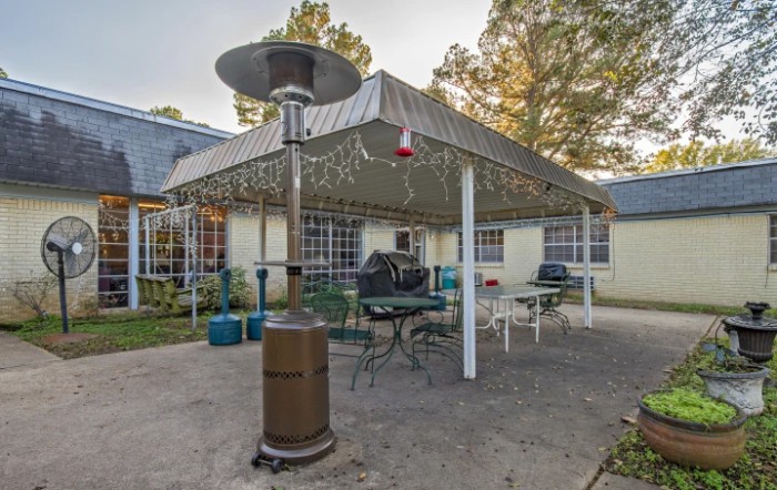 Outdoor patio area with a canopy, string lights, and seating arrangements.