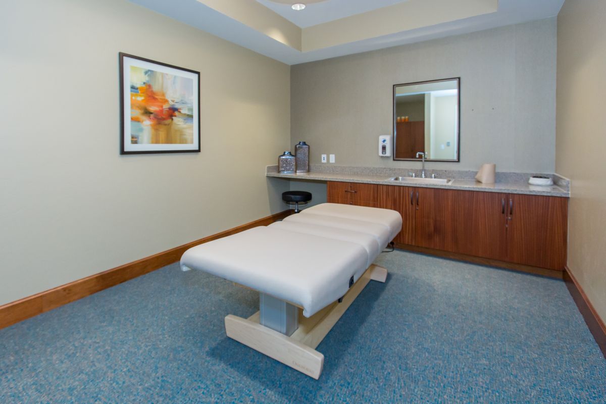 A serene massage room featuring a comfortable treatment bed, soothing lighting, and calming decor.
