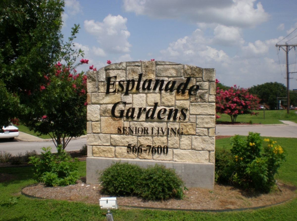 A stone sign for Esplanade Gardens surrounded by greenery.
